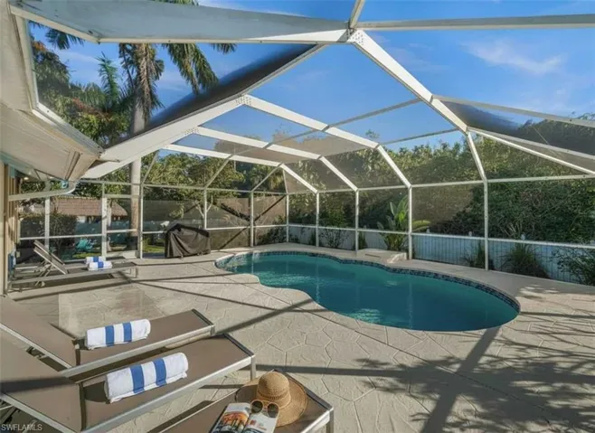 Outdoor pool with a sunroom, glass enclosure, and a patio area