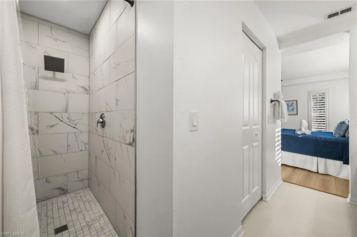 Full bath featuring a stall shower, ensuite bath, and light tile patterned floors