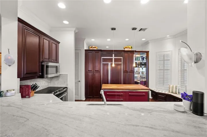 Kitchen with decorative light fixtures, light stone countertops, ornamental molding, recessed lighting, and appliances with stainless steel finishes