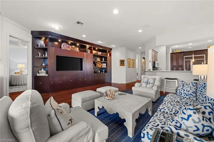 Living room featuring crown molding, wood finished floors, recessed lighting, and built in features