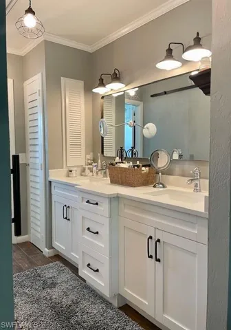 Bathroom featuring ornamental molding, double vanity, a closet, and wood finished floors