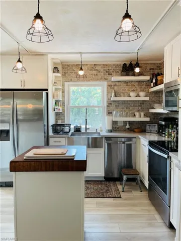 Kitchen featuring open shelves, stainless steel appliances, white cabinetry, light wood finished floors, and a kitchen island