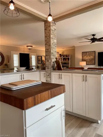 Kitchen with wooden counters, white cabinets, ornamental molding, a ceiling fan, and light wood-style floors