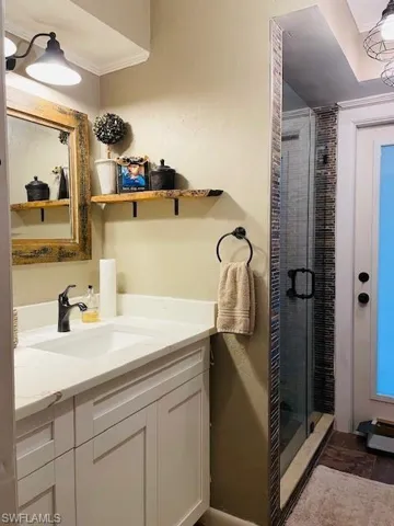 Bathroom featuring a stall shower, vanity, and ornamental molding