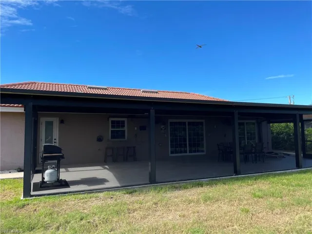 Back of property featuring a patio, stucco siding, a tiled roof, and a yard