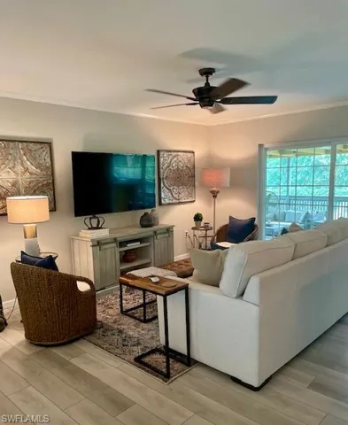 Living room with crown molding, a ceiling fan, and light wood-style floors