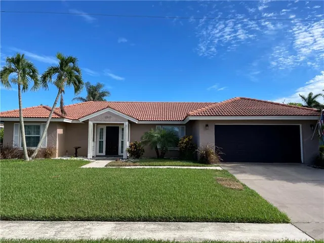 Single story home with stucco siding, an attached garage, a front yard, and driveway