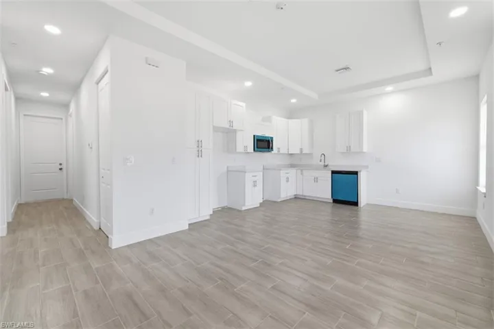 UNIT C- Open-concept living space featuring wood-finish tile flooring, white shaker-style cabinetry, light-toned countertops, and recessed lighting