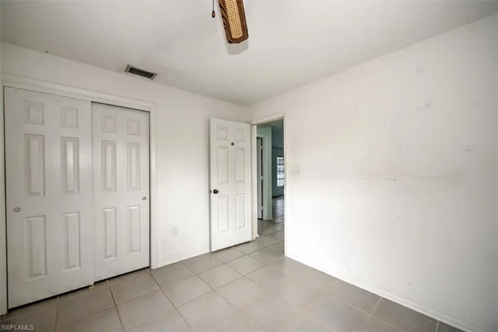 Unfurnished bedroom featuring a textured ceiling, a closet, light tile patterned floors, and ceiling fan