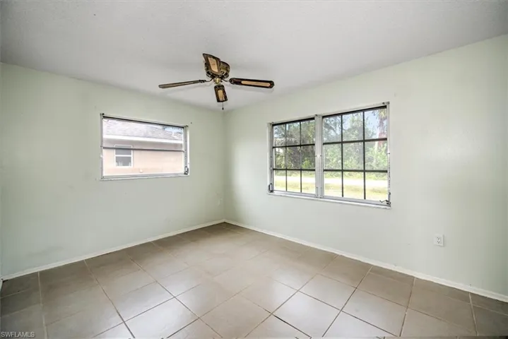 Unfurnished room featuring ceiling fan, a healthy amount of sunlight, light tile patterned floors, and a textured ceiling