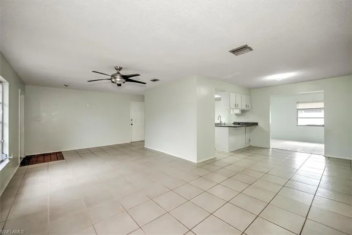 Unfurnished living room with a textured ceiling, ceiling fan, light tile patterned floors, and sink