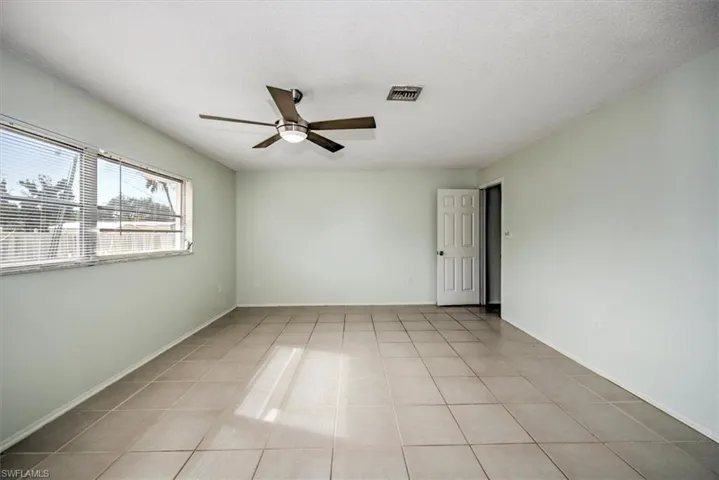 Spare room with a textured ceiling, ceiling fan, and light tile patterned floors