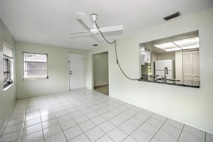 Tiled empty room featuring ceiling fan and a textured ceiling