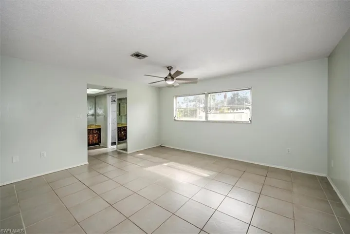 Tiled spare room featuring ceiling fan