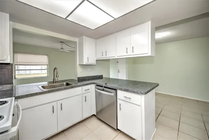 Kitchen featuring white cabinetry, stainless steel dishwasher, and kitchen peninsula