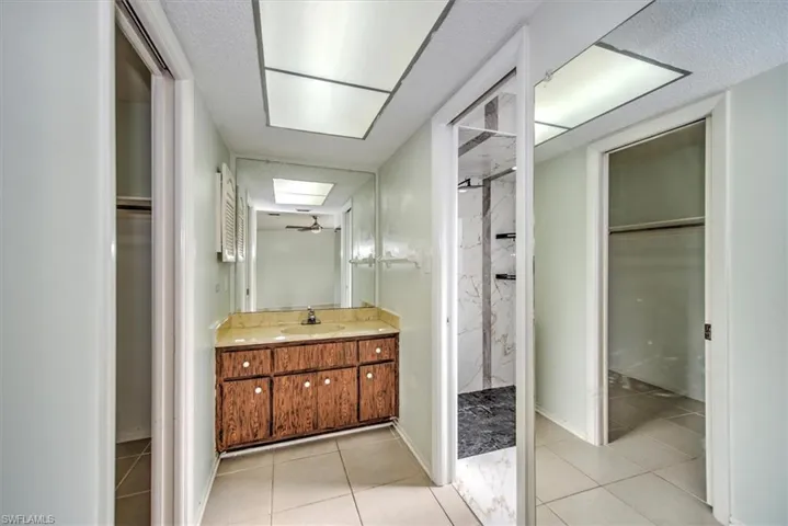 Bathroom featuring a skylight, a shower, ceiling fan, tile patterned flooring, and vanity