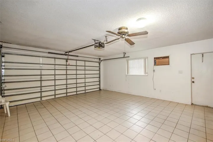 Garage featuring ceiling fan, a garage door opener, and a wall mounted air conditioner