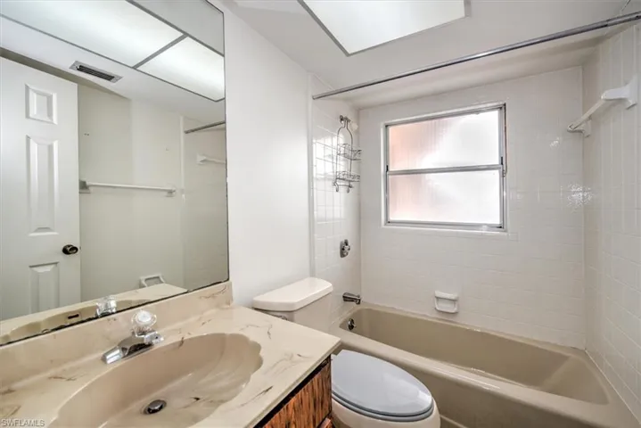 Full bathroom with tiled shower / bath combo, vanity, and toilet
