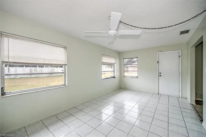 Tiled spare room featuring ceiling fan