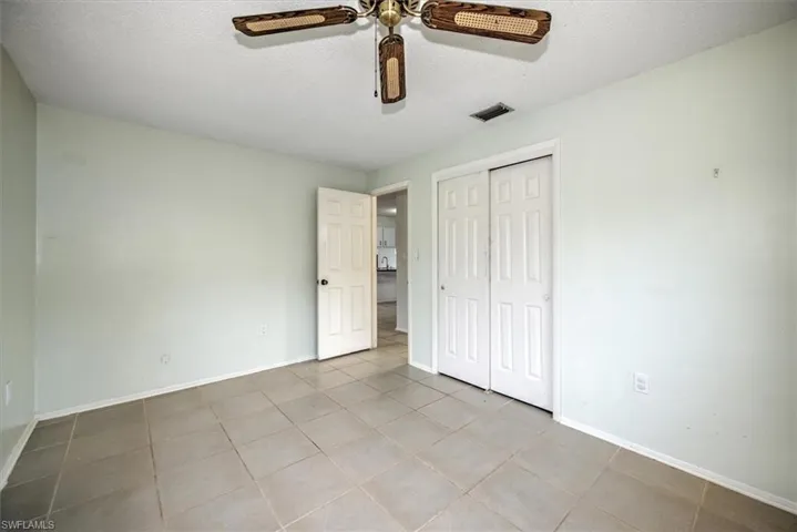 Unfurnished bedroom with ceiling fan, a textured ceiling, light tile patterned floors, and a closet