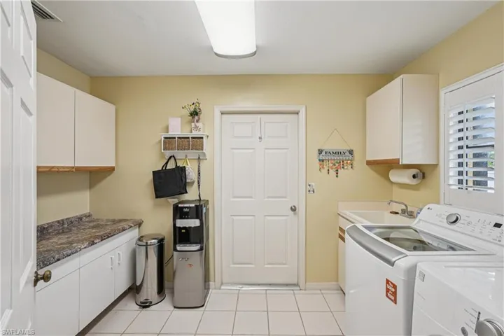 Washroom with cabinet space, light tile patterned floors, and washing machine and clothes dryer