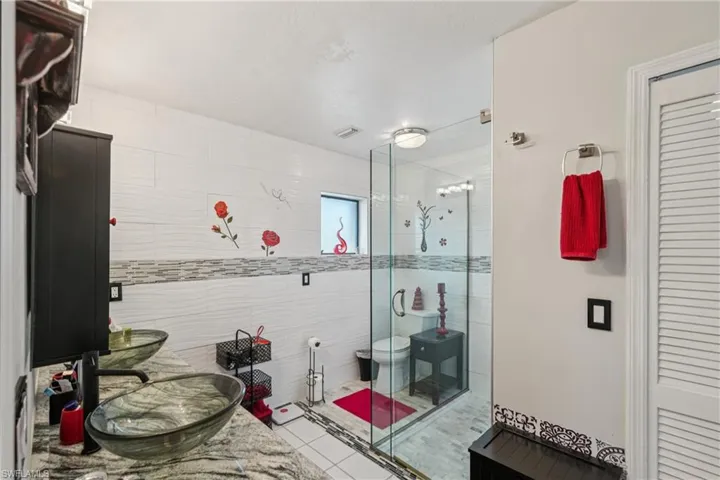 Bathroom with a stall shower, tile patterned flooring, and vanity