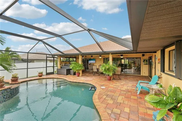 View of swimming pool featuring a sunroom, a patio, glass enclosure, and a ceiling fan