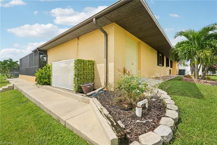 View of side of home with a lawn, stucco siding, and a sunroom