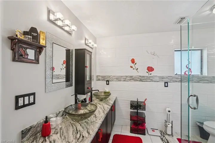 Full bathroom featuring double vanity, light tile patterned floors, and a stall shower