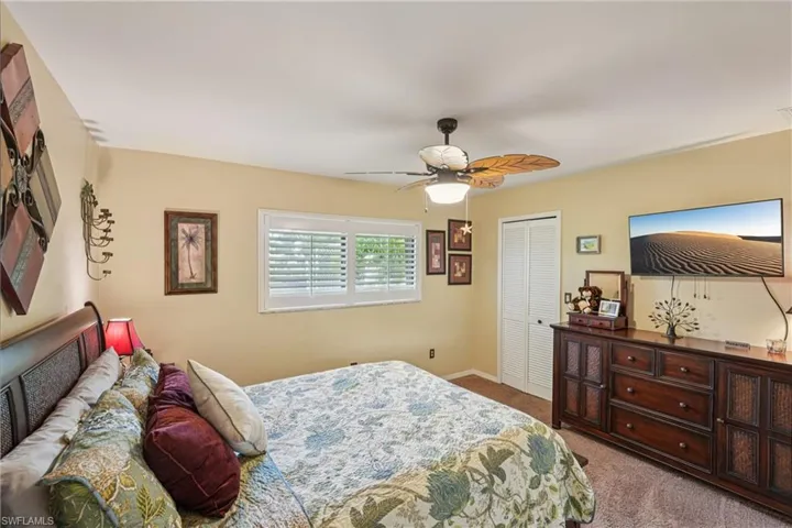 Carpeted bedroom featuring a closet and ceiling fan