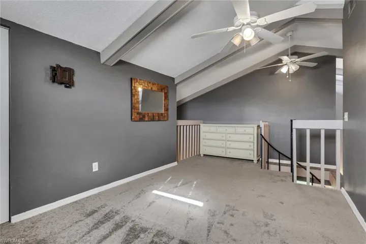 Bonus room featuring carpet, lofted ceiling with beams, and a ceiling fan