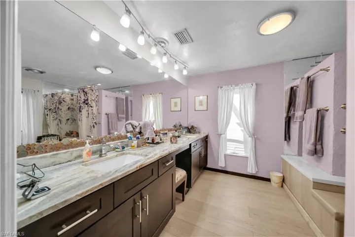 Full bath featuring double vanity, light wood-style flooring, and a shower with shower curtain