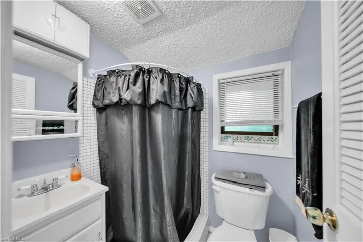 Guest house Bathroom #1 featuring a shower with curtain, a textured ceiling, vanity, and a closet