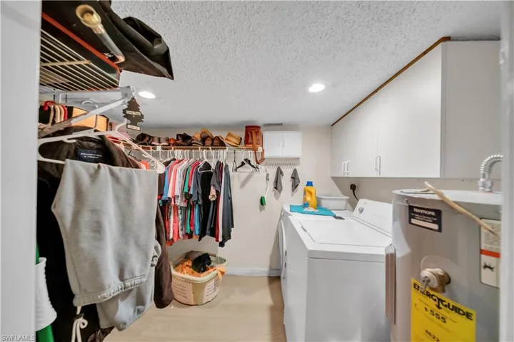 Guest house Laundry room featuring electric water heater, cabinet space, recessed lighting, a textured ceiling, and washer and dryer