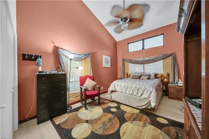 Bedroom with vaulted ceiling, multiple windows, a ceiling fan, and light wood-style flooring