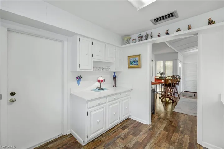 Kitchen with light countertops, visible vents, white cabinetry, and dark wood-type flooring