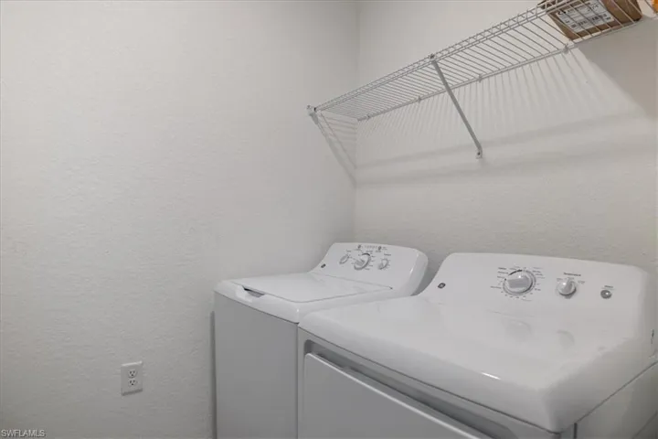 Washroom featuring a textured wall and independent washer and dryer