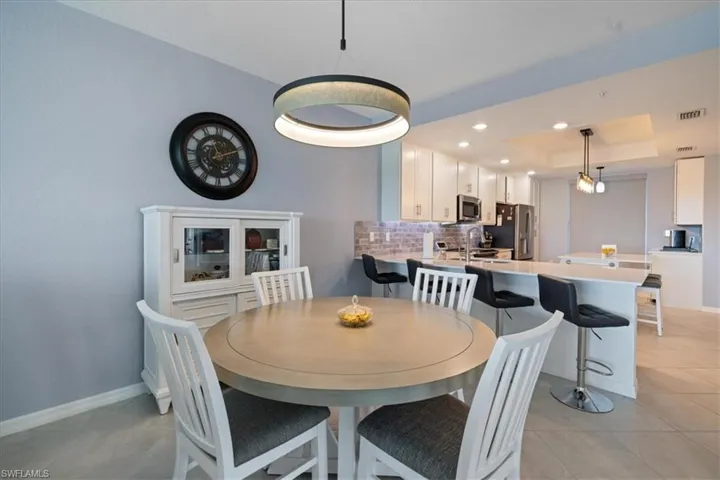Dining room featuring a raised ceiling, recessed lighting, and light tile patterned flooring