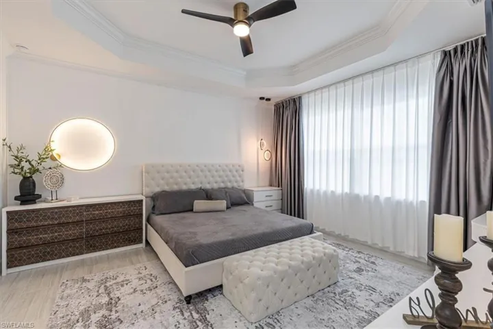 Bedroom with a raised ceiling, crown molding, a ceiling fan, and light wood-type flooring