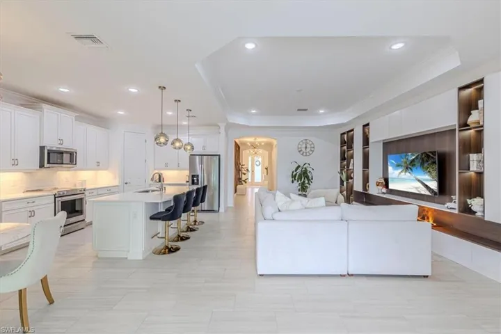Living area with arched walkways, crown molding, recessed lighting, and a tray ceiling