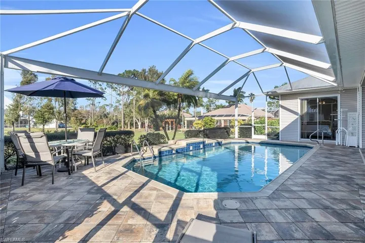 Custom heated pool with waterfall and unobstructed screen view of yard