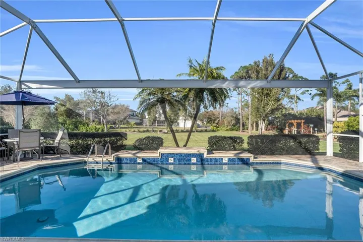 Custom heated pool with waterfall and unobstructed screen view of yard