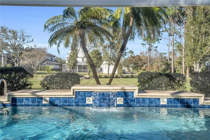 Custom heated pool with waterfall and panoramic screen view of yard