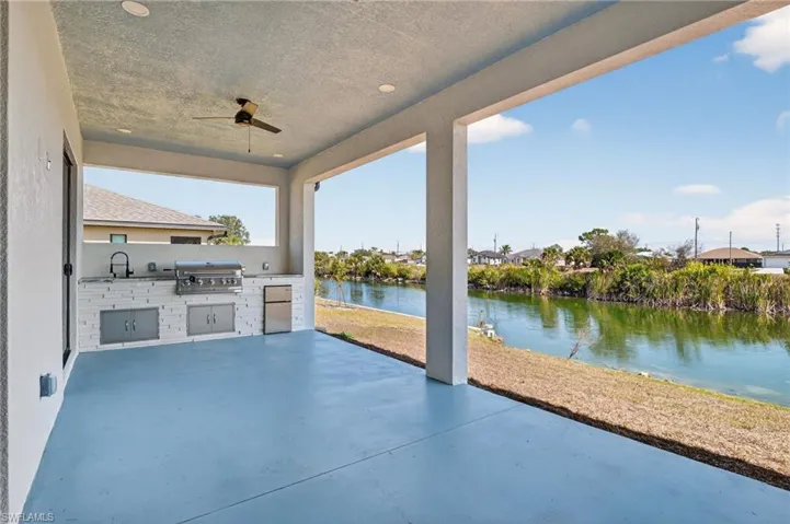 Lanai with outdoor kitchen, ceiling fan, and canal view