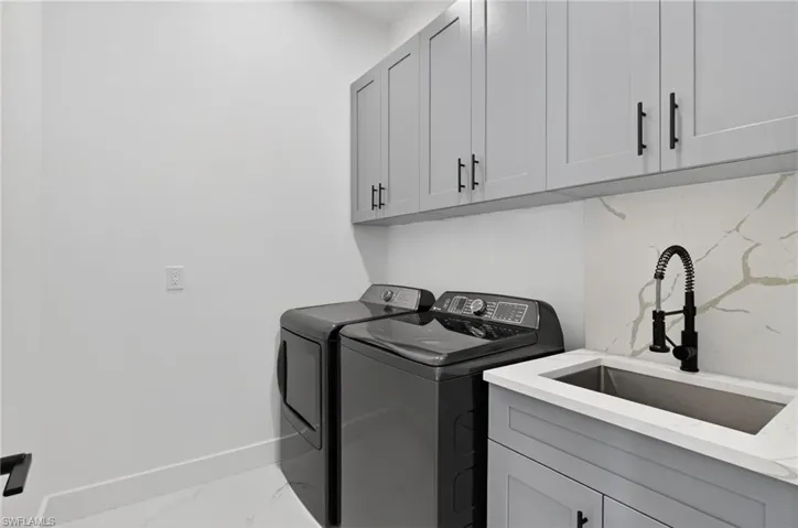 Laundry room with separate washer and dryer, and cabinets.