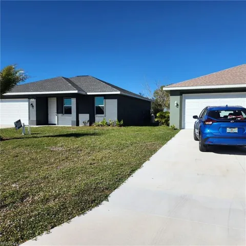 View of side of home featuring stucco siding, a lawn, and concrete driveway