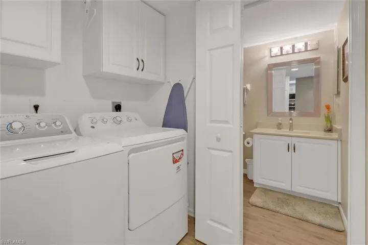 Washroom with light hardwood / wood-style floors, separate washer and dryer, cabinets, and sink