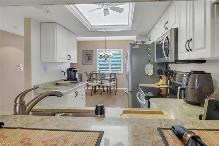 Kitchen featuring white cabinetry, light hardwood / wood-style flooring, ceiling fan with notable chandelier, light stone countertops, and range with electric cooktop