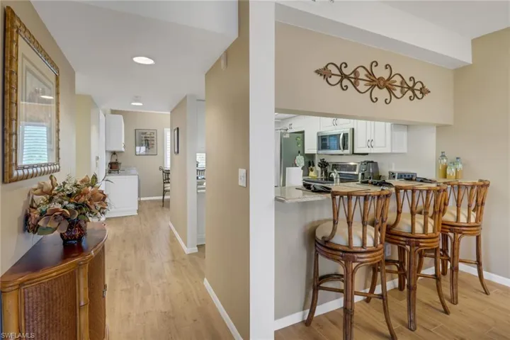 Kitchen featuring white cabinetry, stainless steel appliances, light hardwood / wood-style flooring, and a breakfast bar area