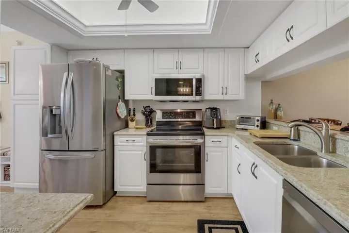 Kitchen with ceiling fan, sink, light hardwood / wood-style flooring, and stainless steel appliances